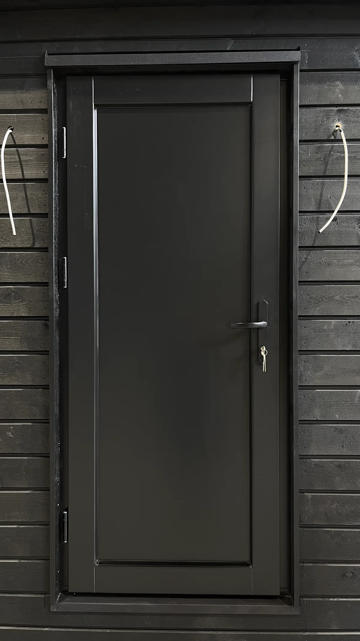 Чёрная входная деревянная дверь с многоточечным замком GU на серой деревянной обшивке