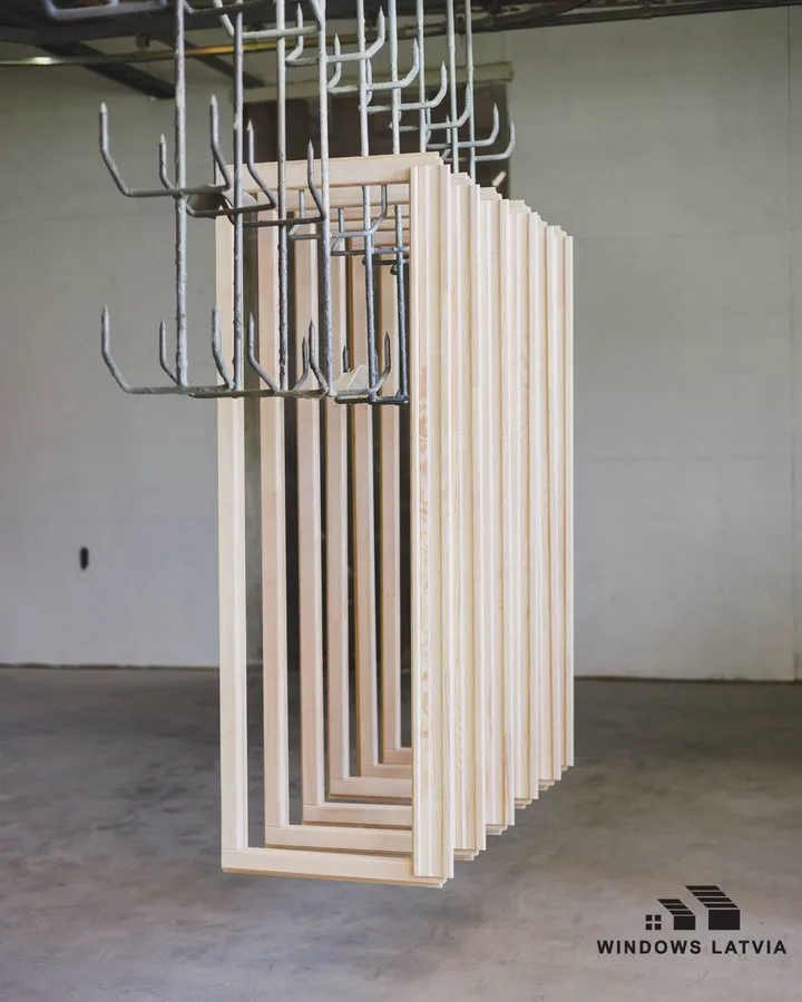 Краска для деревянных окон: рамы на крюках сушки после покраски на фабрике Windows Latvia в Калнциемсе
