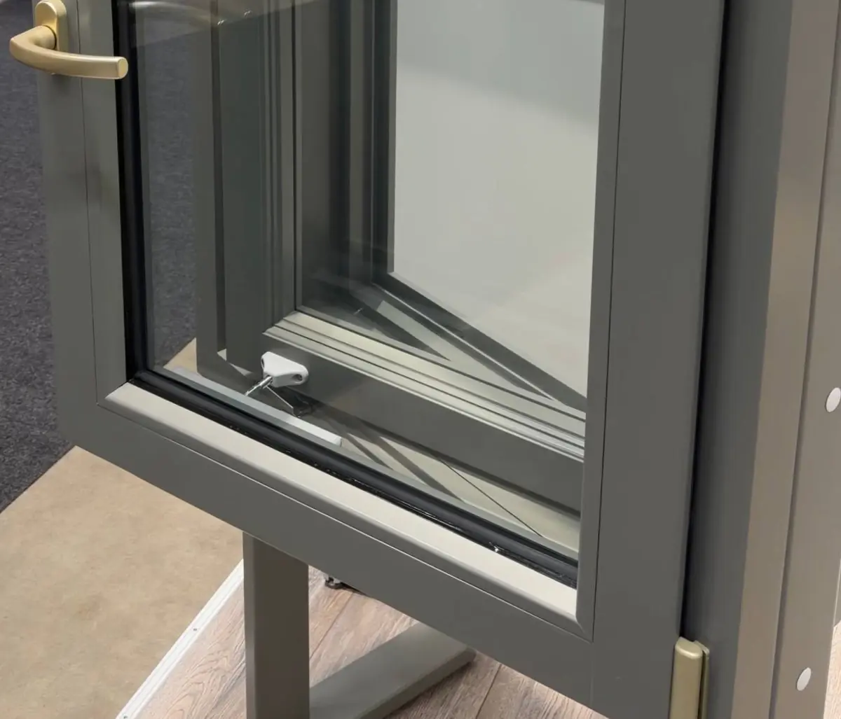 Timber double window sample opened into the room, the inner window in front and the outer window swung in with it, grey-green paint and a brass-coloured handle