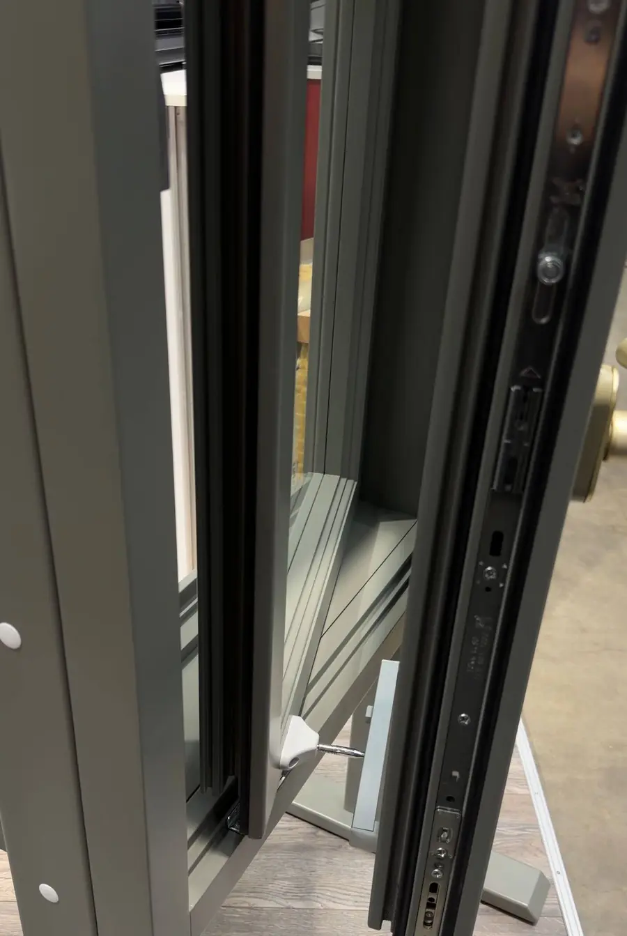 Close-up of an opened timber double window, showing the multi-point lock on the edge of the inner window, the turn catch linking the outer window to it, and the timber frame between them